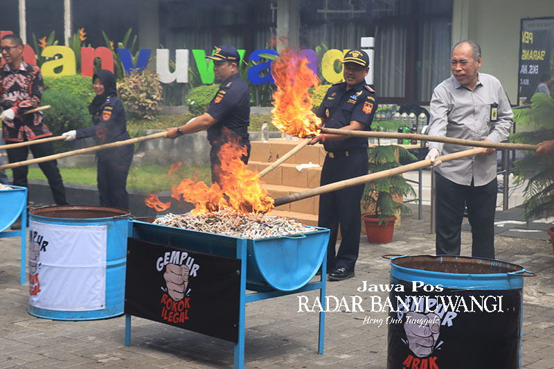 LINDUNGI KONSUMEN: Petugas memusnahkan ribuan rokok ilegal dan miras ilegal di halaman kantor Bea Cukai Banyuwangi, Selasa (5/12).