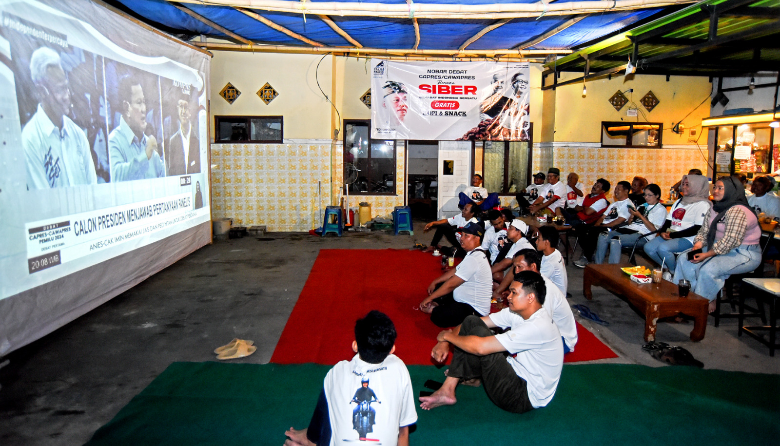 DUKUNGAN NYATA: Sejumlah relawan menyaksikan debat capres di salah satu posko pemenangan Ganjar-Mahfud di Kelurahan Kampung Mandar, Kecamatan Banyuwangi, Selasa malam (12/12).