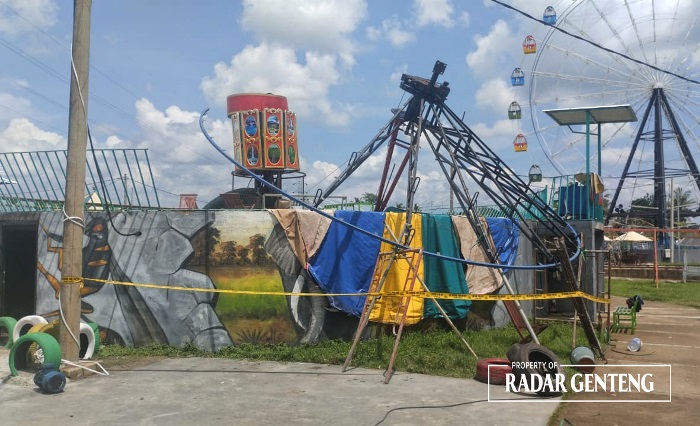 HARUS STERIL: Anggota Unit Reskrim Polsek Genteng memasang garis polisi di lokasi wahana Swinger yang ambruk di wisata Banyuwangi Night Amaizing (BNA) Desa Genteng Wetan,Kecamatan Genteng.