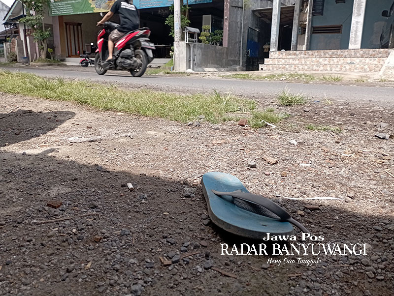 Sandal jepit milik teman Aditya Warman yang tertinggal di tepi jalan raya Dusun Krajan, Desa Kradenan, Kecamatan Purwoharjo, Banyuwangi, Rabu (27/12).