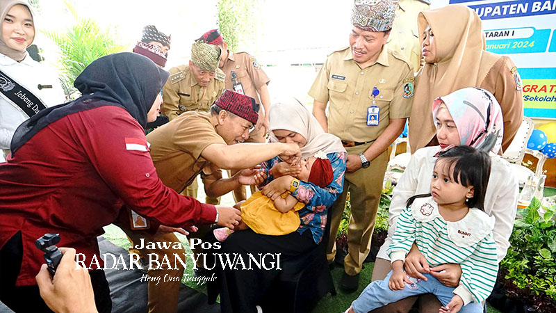 PENCEGAHAN: Asisten Pemerintahan dan Kesra Pemkab Banyuwangi Arief Setiawan didampingi Plt. Kepala Dinkes Amir Hidayat memberikan vaksinasi polio tetes kepada salah satu anak di Mojopanggung, Giri.