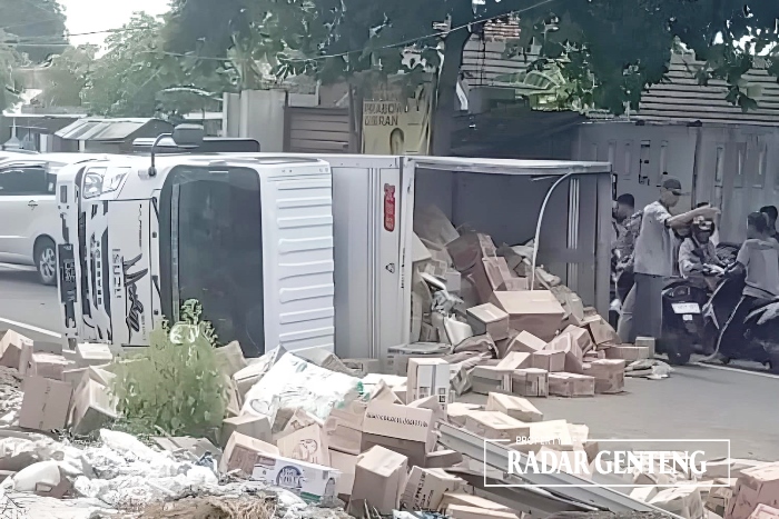 BERHAMBURAN: Truk Isuzu Elf terguling usai menabrak sepeda motor Honda Scoopy di depan bengkel Desa Benculuk, Kecamatan Cluring Minggu (21/1).