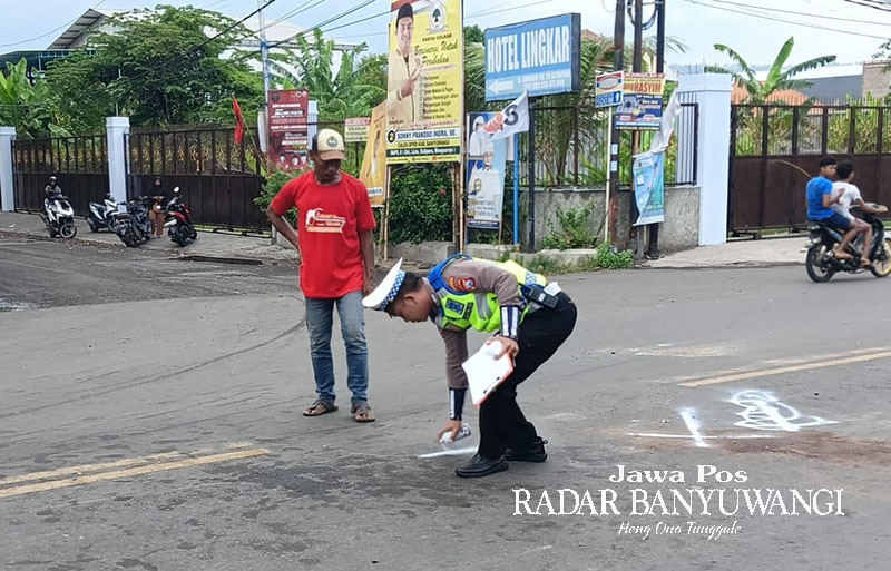 DITANDAI CAT PUTIH: Anggota Satlantas Polresta Banyuwangi melakukan olah TKP kecelakaan di pertigaan jalan lingkar Ketapang, Kalipuro, Minggu (28/1).
