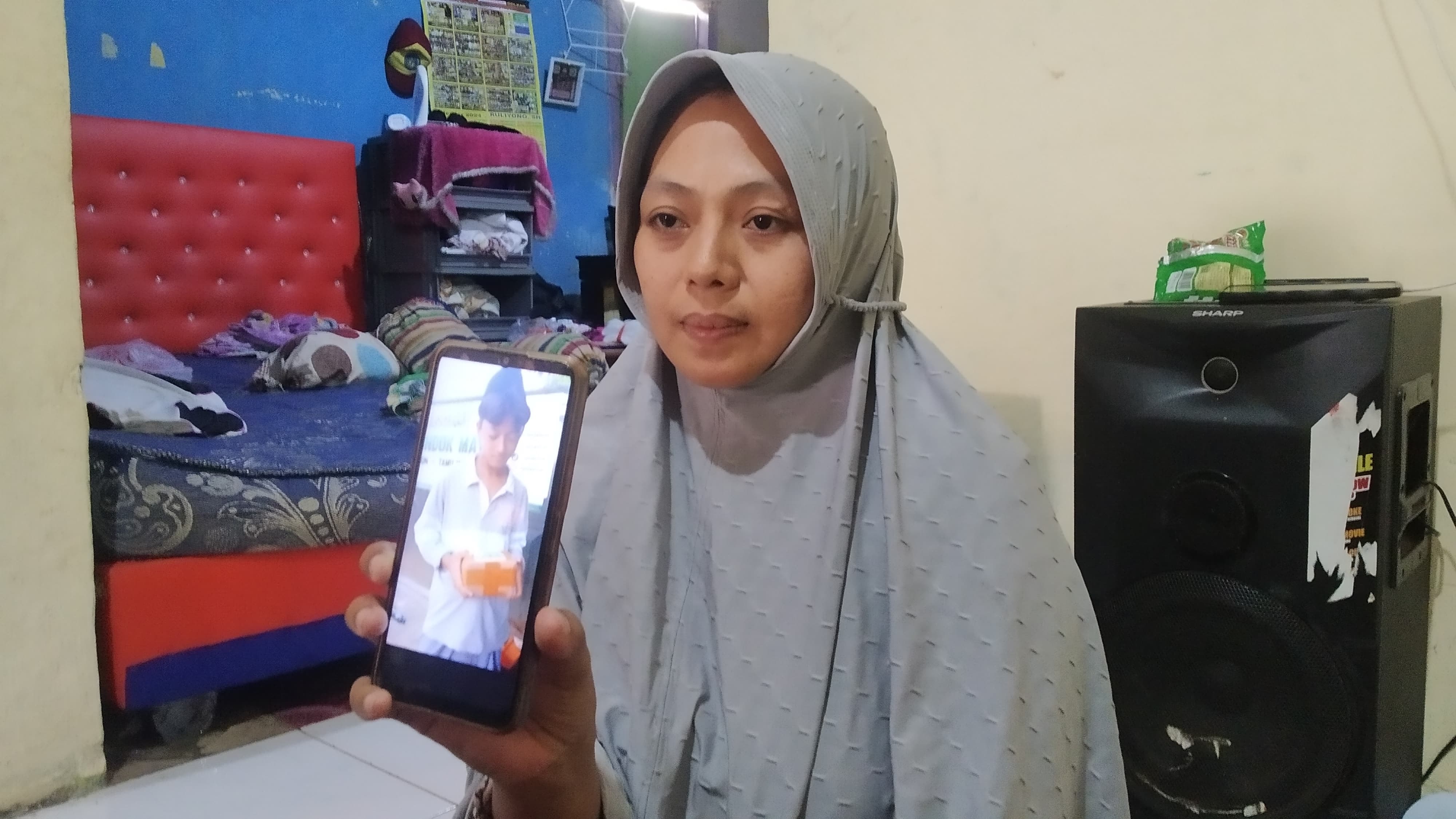 POTONGAN MEMORI: Suyanti menunjukkan foto Bintang yang dipajang di dinding rumahnya di Dusun Kendenglembu, Desa Karangharjo, Kecamatan Glenmore pada Selasa (27/2).