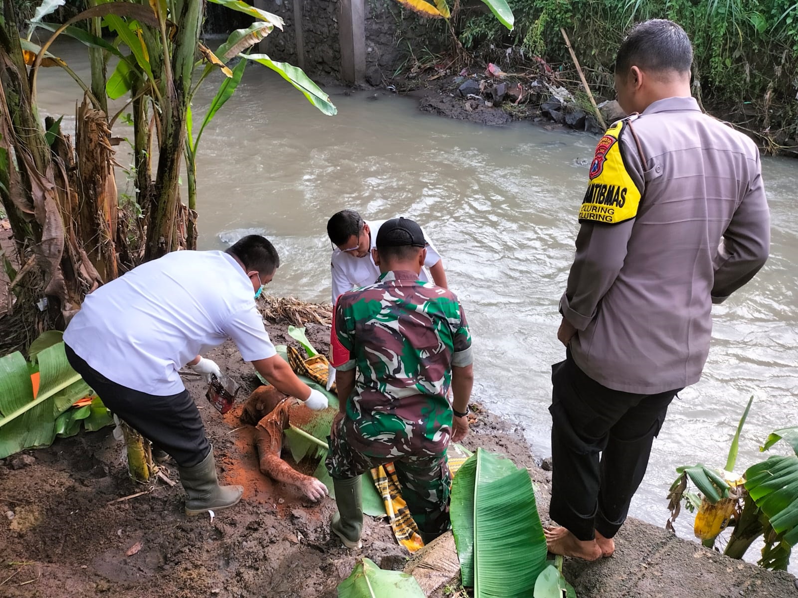 JATUH: Jenazah Dodik Saputro dievakuasi petugas medis bersama anggota Polsek dan Koramil Cluring dari Sungai Simbar di Dusun Karangrejo, Desa/Kecamatan Cluring kemarin (4/3).