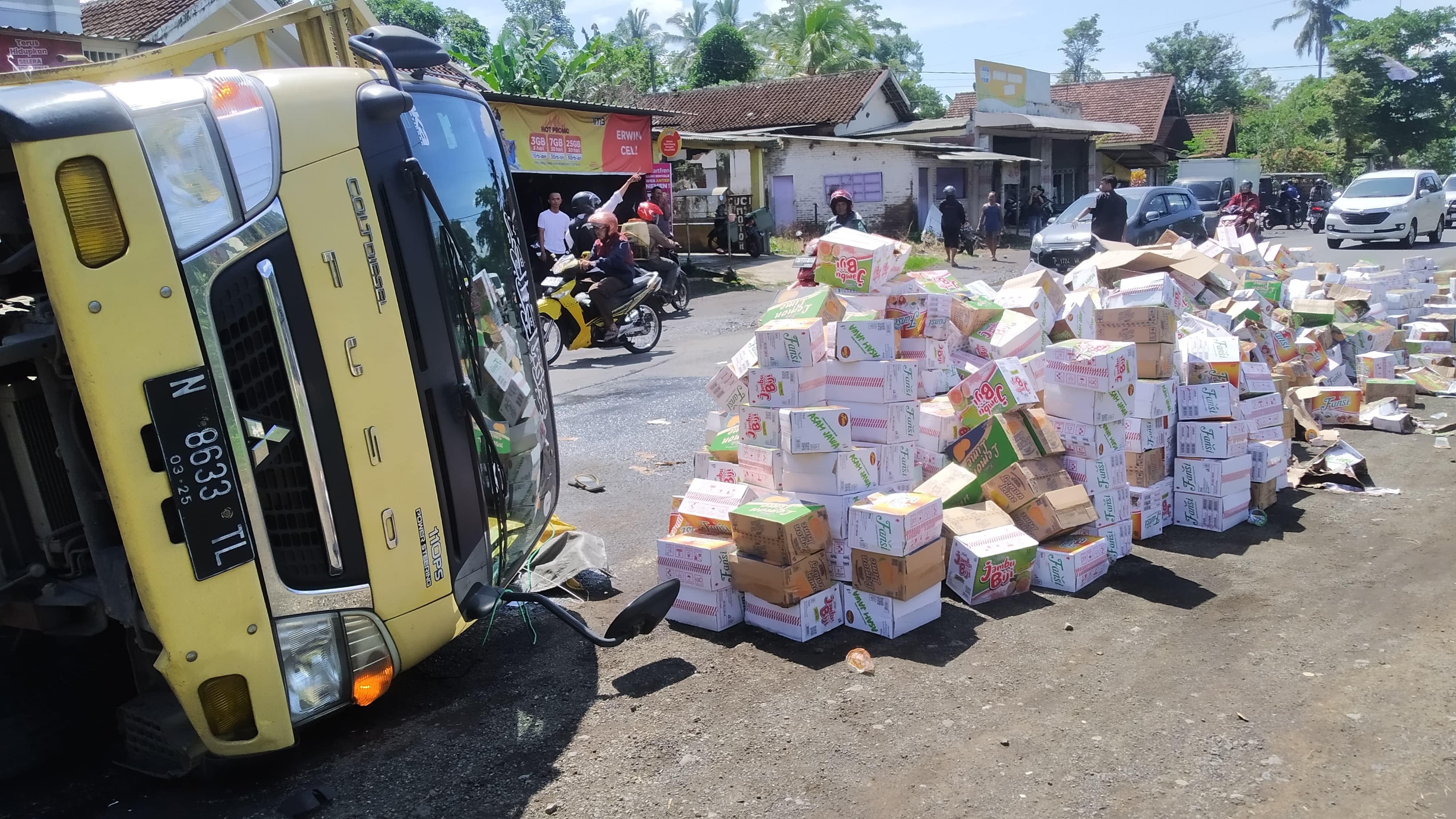 BERSERAKAN: Ribuan kardus minuman berserakan di jalan akibat truk yang membawa terguling di jalan raya Dusun Wadung Dollah, Desa Setail, Kecamatan Genteng Selasa (5/3).