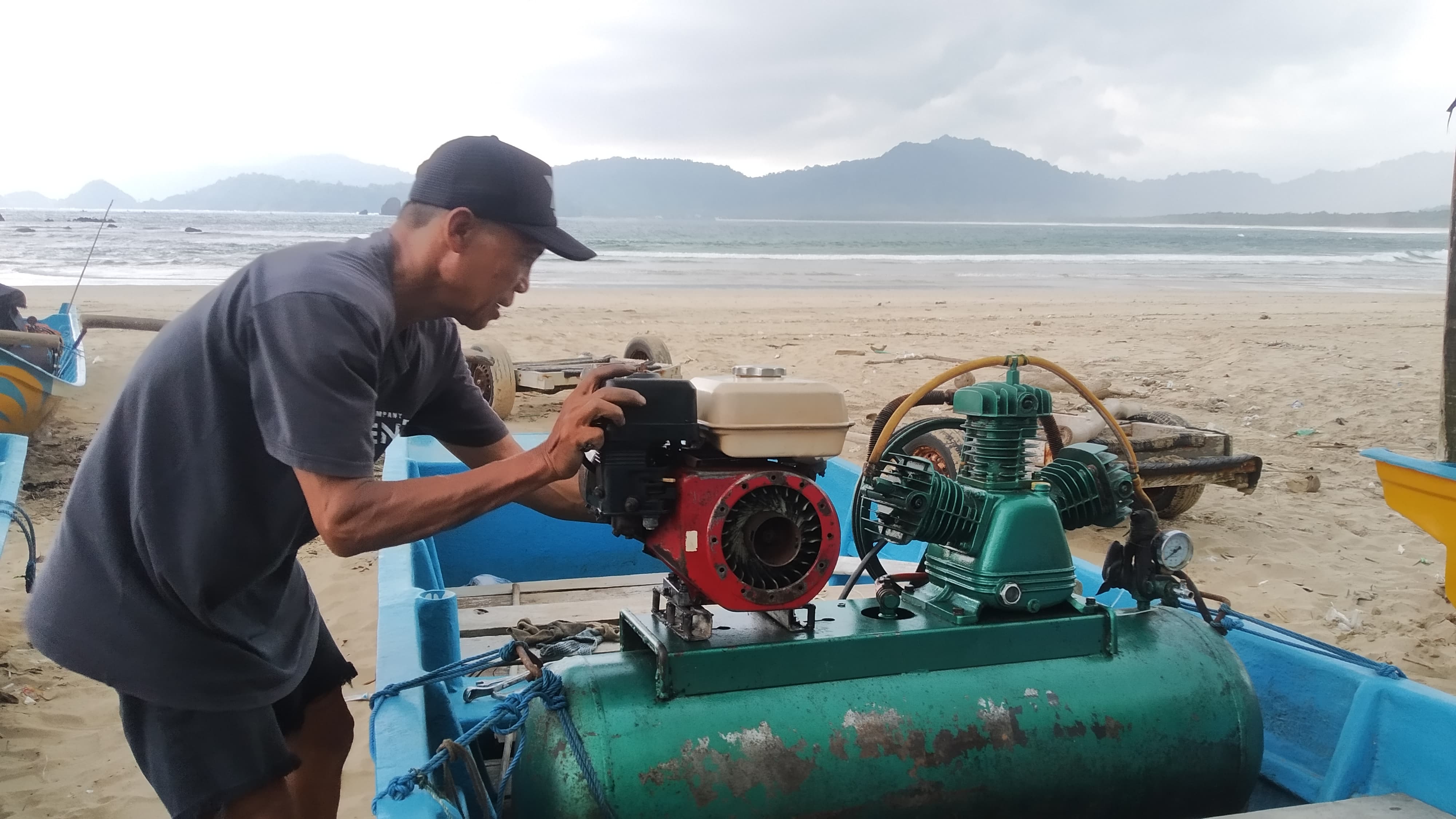 TIDAK BEKERJA: Suigantoro memperbaiki mesin kapalnya saat tidak melaut akibat cuaca buruk di Pantai Pulau Merah, Desa Sumberagung, Kecamatan Pesanggaran Minggu (10/3).