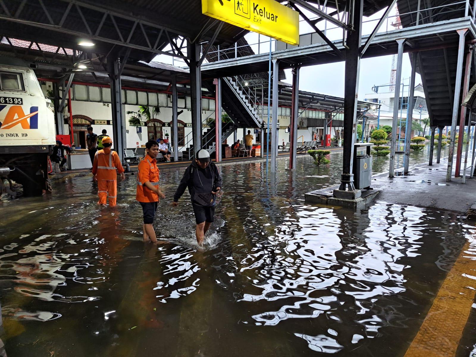 Penumpang berjalan melewati genangan air di Stasiun Semarang Tawang.