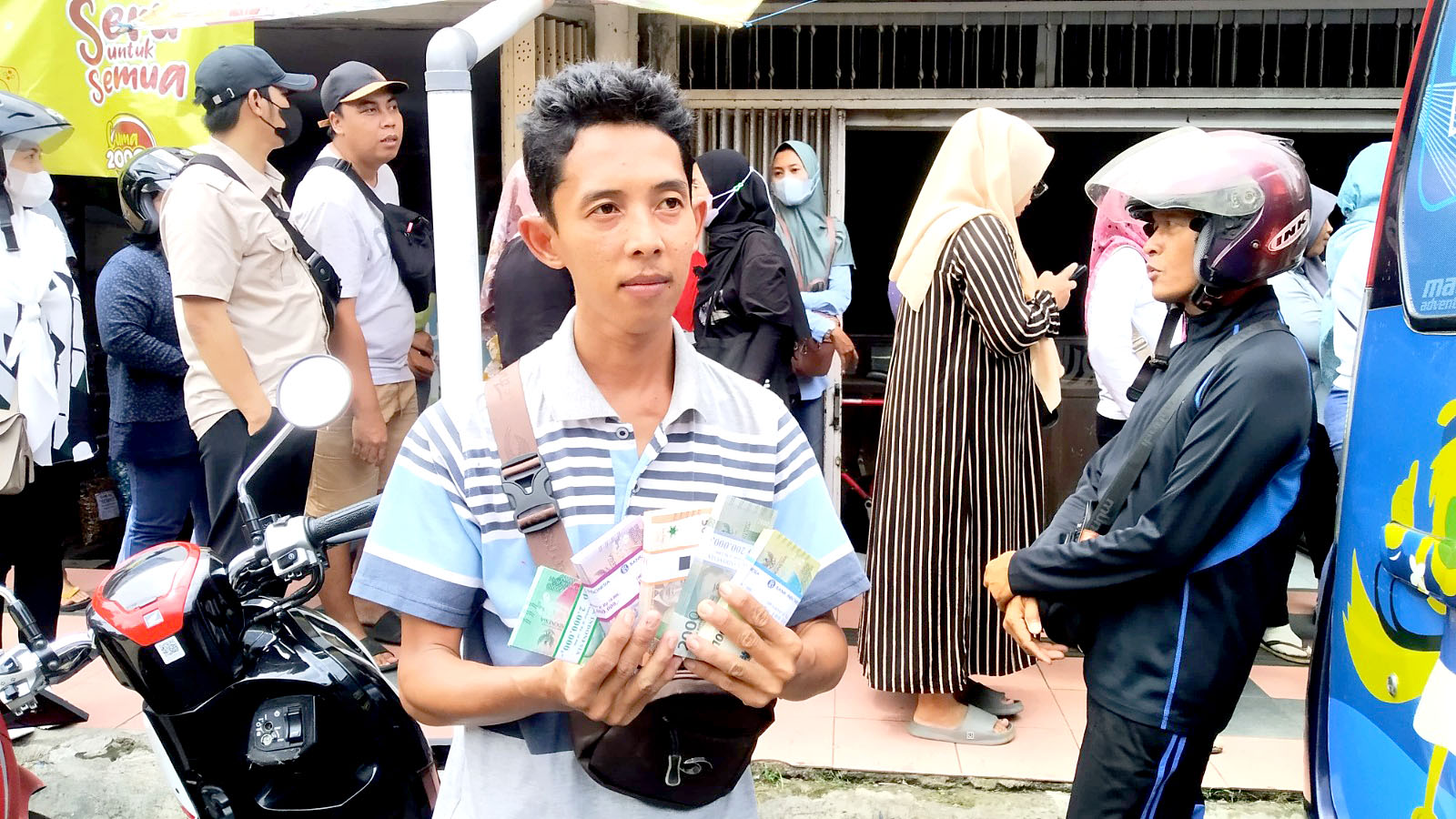 UANG BARU: Bagus Aditya Prasetya menunjukkan hasil penukaran uang di BI di depan Pasar Induk Genteng 1, Desa Genteng Kulon, Kecamatan Genteng pada Rabu (13/3).
