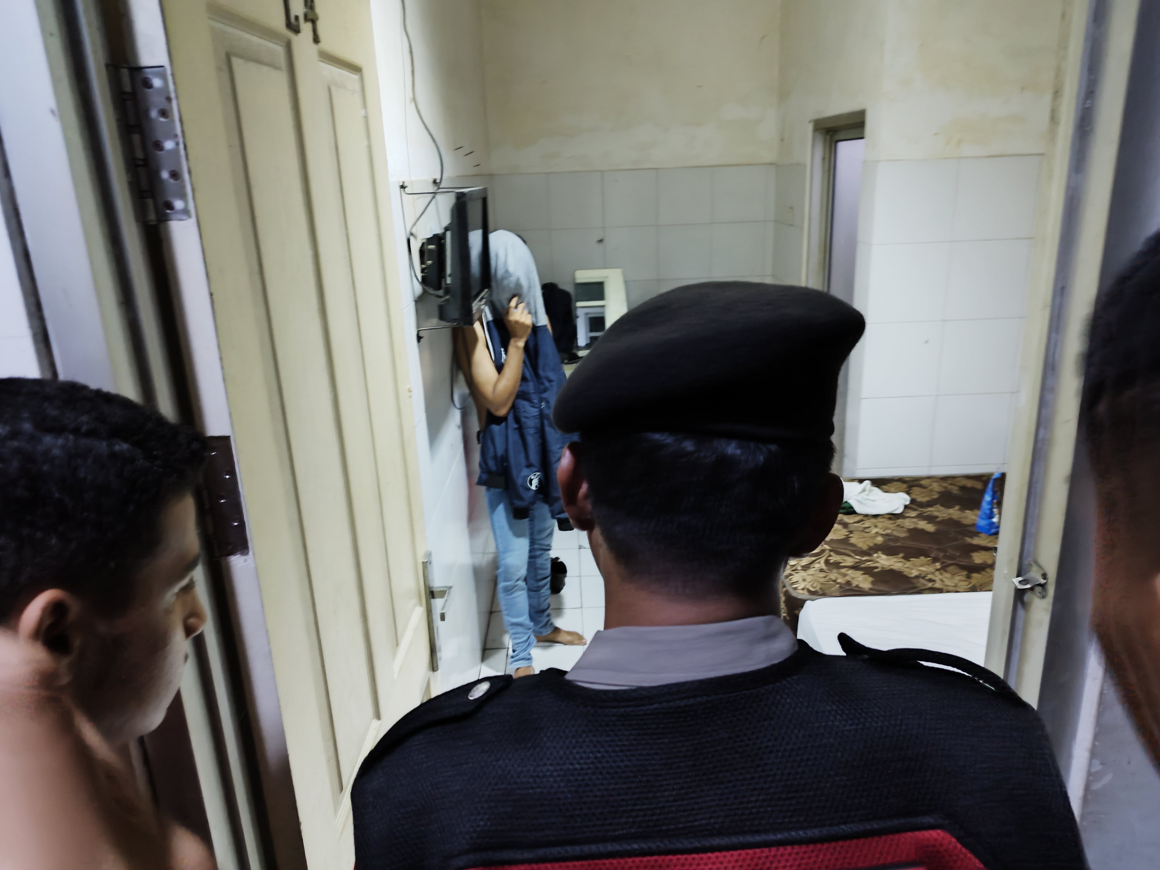 WAJAHNYA DITUTUP JAKET: Kasat Samapta AKP Basori Alwi (kanan) menginterogasi penghuni kamar Hotel Brawijaya, Kelurahan Mojopanggung, Rabu malam (20/3).