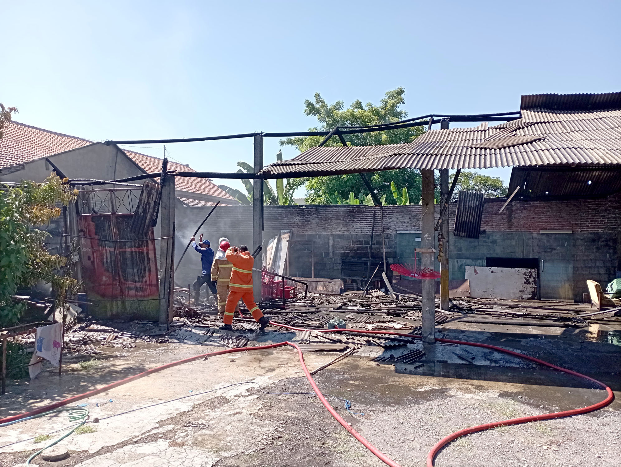 HANGUS: Petugas Damkarmat wilayah Banyuwangi berusaha memadamkan api yang membakar gudang penyimpanan barang bekas di Kelurahan Tukangkayu Senin (15/4).