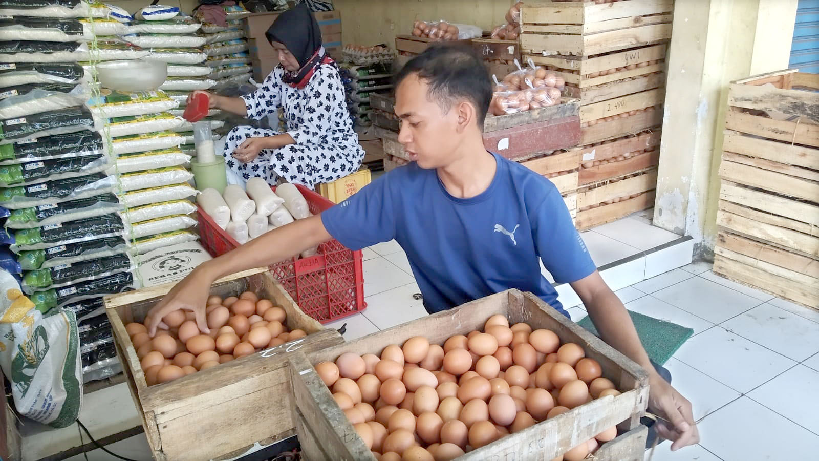 TETAP: Ardan Nur Rofi menata stok telur di toko sembako di Pasar Genteng 2, Desa Genteng Kulon, Kecamatan Genteng, Kamis (18/4).