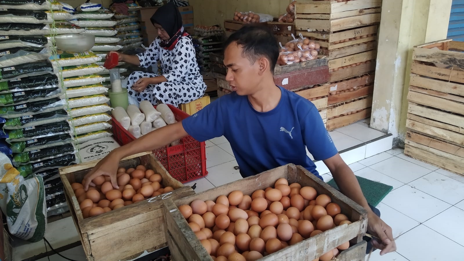 TETAP: Ardan Nur Rofi menata stok telur di toko sembako di Pasar Genteng 2, Desa Genteng Kulon, Kecamatan Genteng Kamis (18/4)