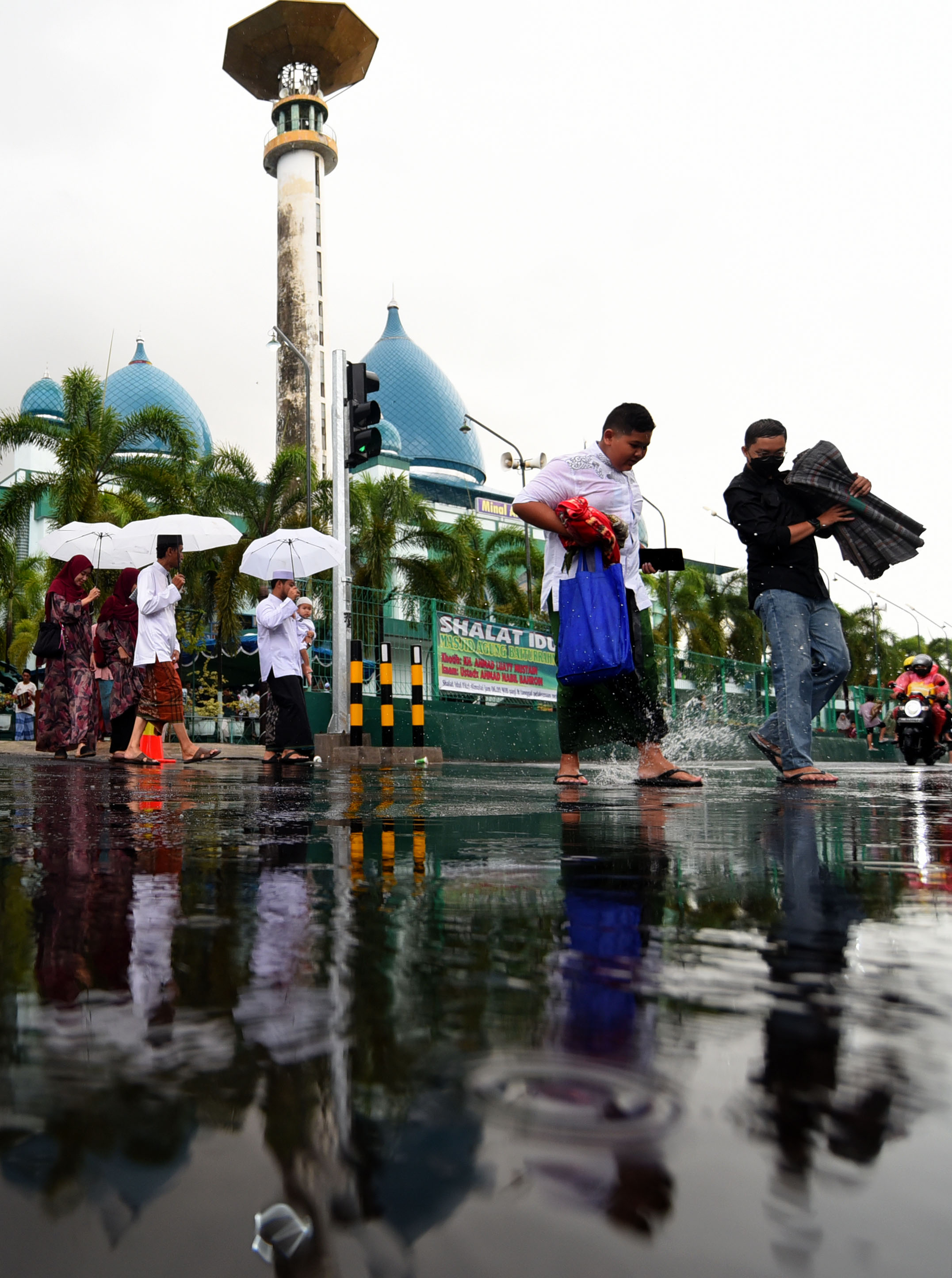 PENUTUP AURAT: Umat Islam keluar dari Masjid Agung Baiturrahman Banyuwangi saat hujan. Ada yang mengenakan sarung, ada juga yang mengenakan celana