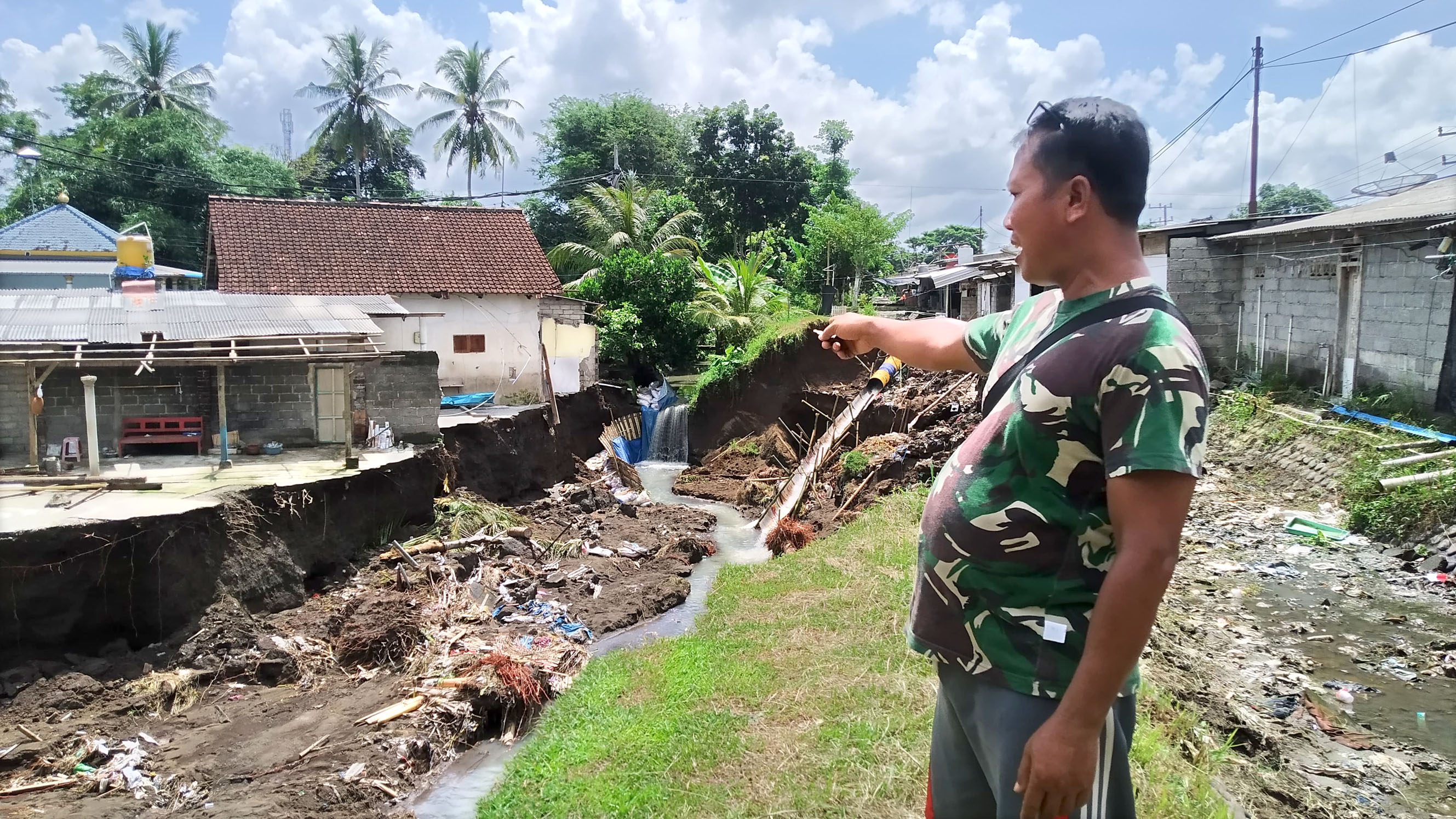 TERANCAM: Mustakim menunjukkan bibir Sungai Apur di Dusun Krajan, Desa/Kecamatan Siliragung yang ambrol mengancam rumah dan ruko Jumat (19/4).