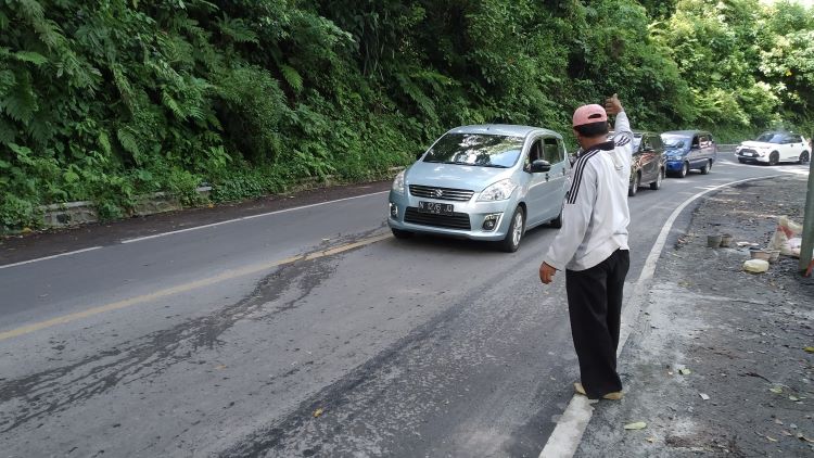 MIRING: Kendaraan yang melewati jalur Gumitir mengurangi kecepatan karena jalan miring akibat retak di Dusun/Desa Sidomulyo, Kecamatan Silo, Kabupaten Jember Minggu (21/4).