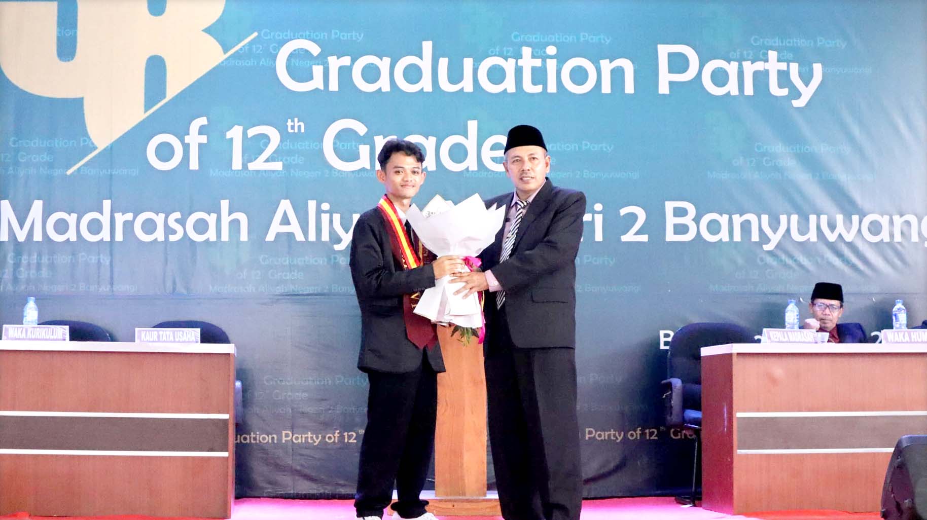 MEMBANGGAKAN: Kepala MAN 2 Banyuwangi Drs H Saeroji MAg (kanan) memberikan buket kepada Fito Uki Syahrul Ramadan talenta muda dari Universitas Malang jurusan Kesehatan Masyarakat