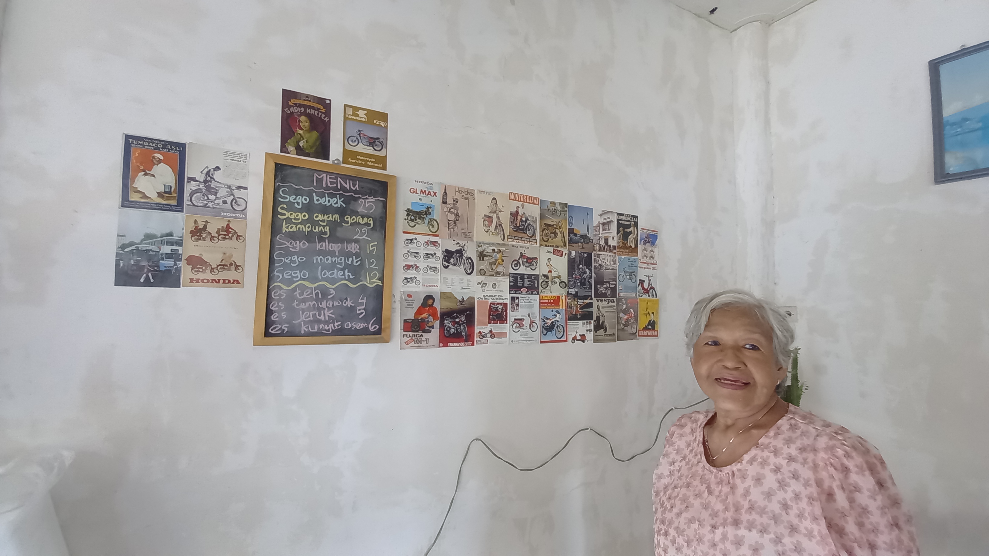 RESEP AWET MUDA: Rasmiati mengoleksi poster lawas mulai usia 10 tahun. Poster tersebut menghiasi dinding warungnya di Jalan Surati, Banyuwangi.