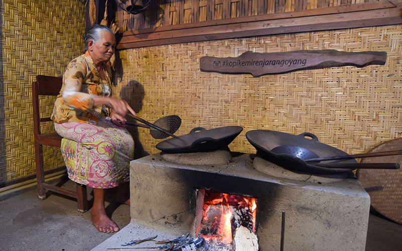 TIDAK PUNAH: Seorang perempuan tua memasak dengan menggunakan anglo permanen yang didukung bahan bakar kayu di Desa Kemiren, Kecamatan Glagah, Banyuwangi.