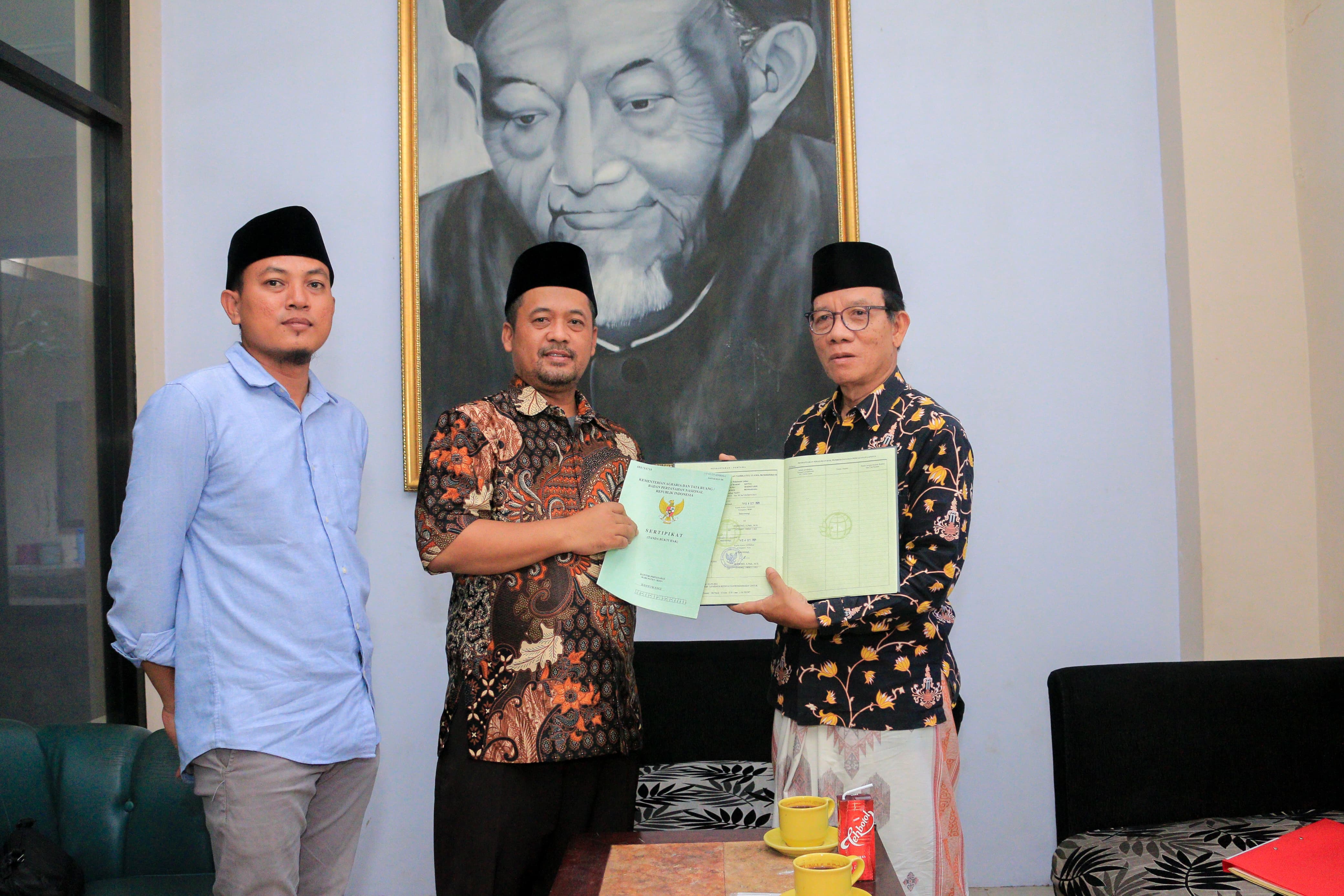 ASET ORGANISASI: Nasir Basrawi (kanan) menyerahkan sertifikat tanah wakaf RSNU kota dan sertifikat tanah kantor PCNU Banyuwangi kepada Koordinator Pengurus Harian PCNU Karteker Abdul Aziz (tengah).