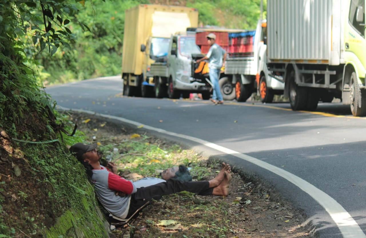 Sopir truk tidur saat proses evakuasi truk terguling di Jalur Gumitir (12/5/2023) lalu