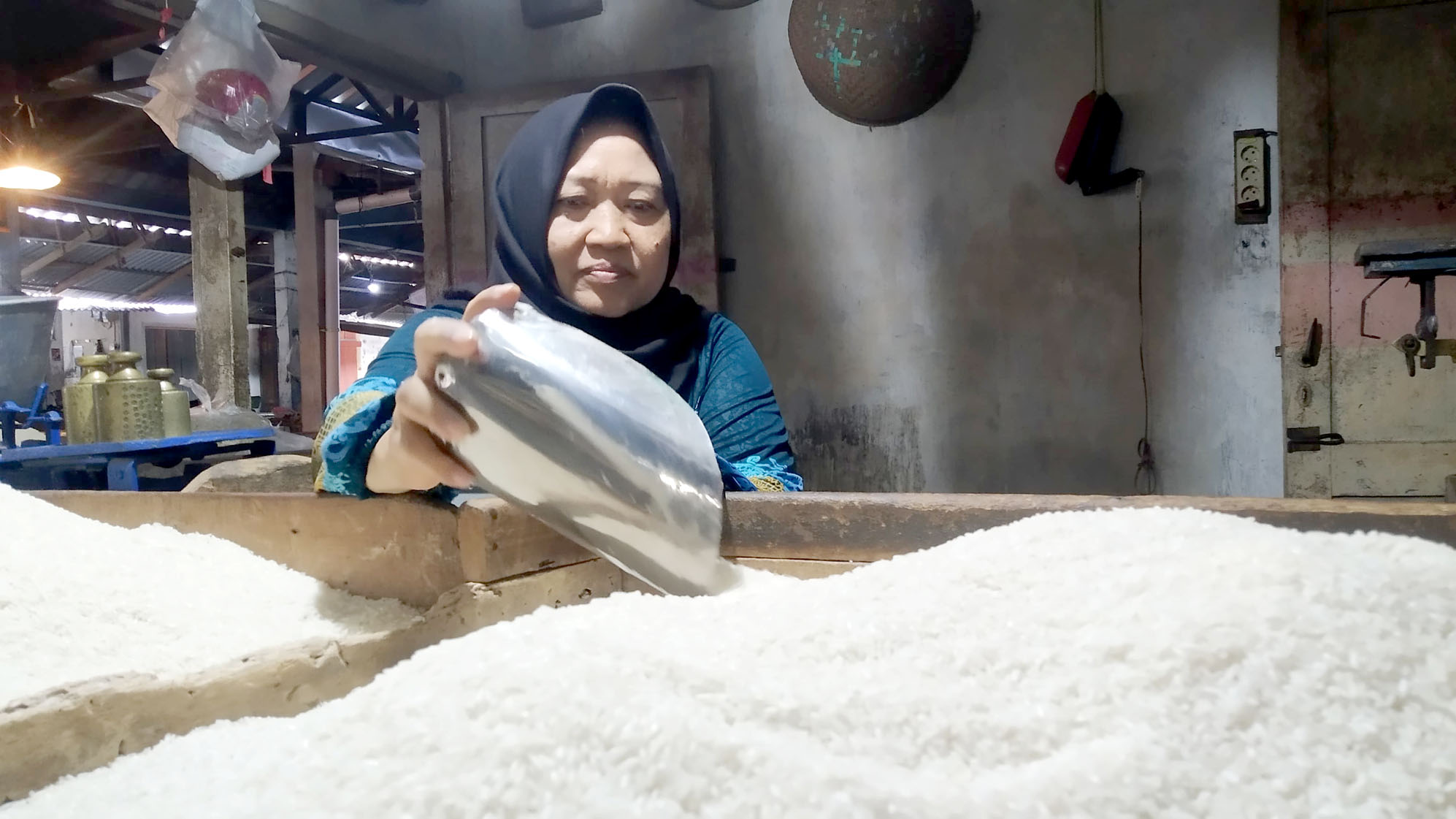 MURAH: Titin Sumarni menata beras dagangannya di Pasar Genteng 2, Desa Genteng Kulon, Kecamatan Genteng Minggu (5/5).