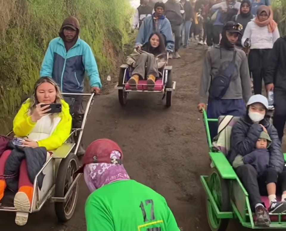 Wisatawan turun dari puncak Kawah Ijen, Banyuwangi dengan menumpang troli.