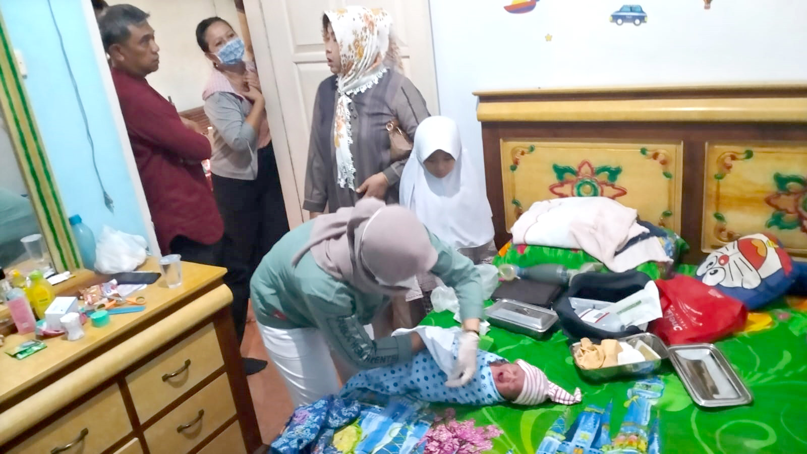 DIRAWAT BIDAN: Kapolsek Rogojampi Kompol Imron saat melihat bayi laki-laki yang ditemukan di depan rumah warga di Dusun Gepuro, Desa Watukebo Kecamatan Blimbingsari, Sabtu (18/5)