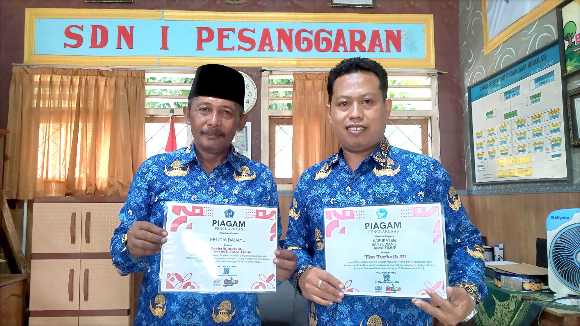 BANGGA: Slamet Riyadi (kiri) dan Nur Sugeng Prasetyo  menunjukkan piagam prestasi Felicia Dahayu di SDN 1 Pesanggaran, Kecamatan Pesanggaran Senin (20/5).