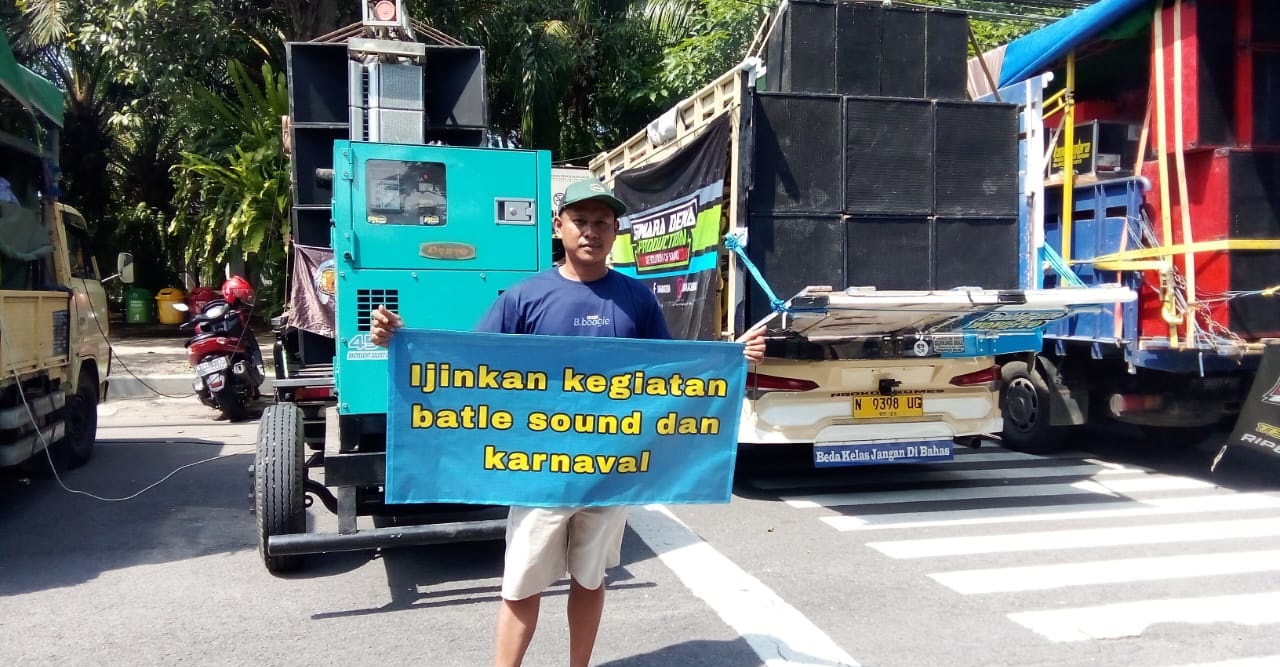 Salah satu peserta demo yang tergabung dalam Aliansi Paguyuban Sound menunjukkan banner tuntutan di depan Kantor Pemkab Banyuwangi, Rabu siang (22/5).