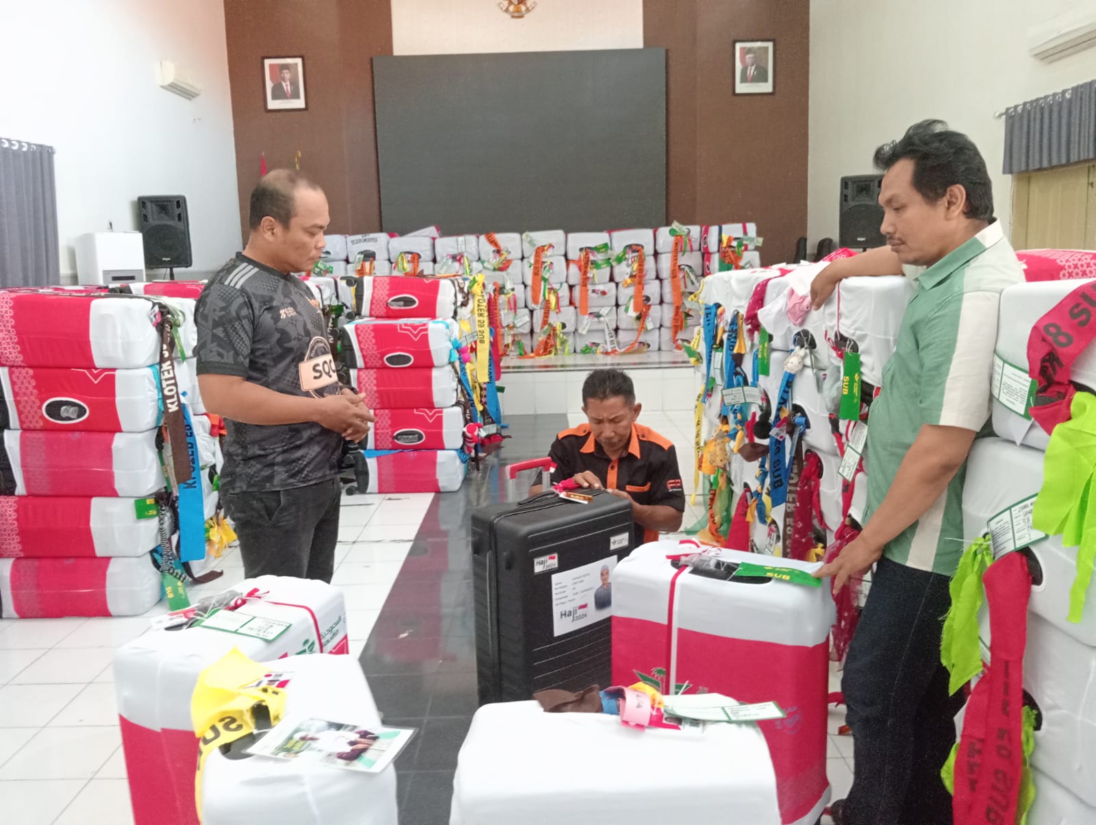 PERIKSA ISI KOPER: Ketua Kloter 58 Syafaat (kiri) mengamankan laptop milik CJH yang disimpan dalam koper besar. Seluruh koper haji kemarin sudah dikirim ke asrama haji Surabaya.