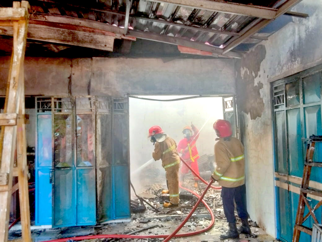 BERJIBAKU: Petugas damkarmat memadamkan api yang membakar salon kecantikan milik Ita Sariana di Dusun Umbulrejo, Desa Bagorejo, Kecamatan Srono Minggu (2/6) sore.