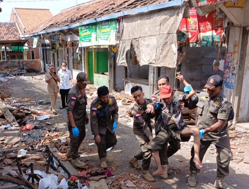 DIEVAKUASI: Anggota Satpol PP Banyuwangi mengamankan seorang kakek yang didapati tidur di lokasi revitalisasi Pasar Banyuwangi Selasa (11/6).