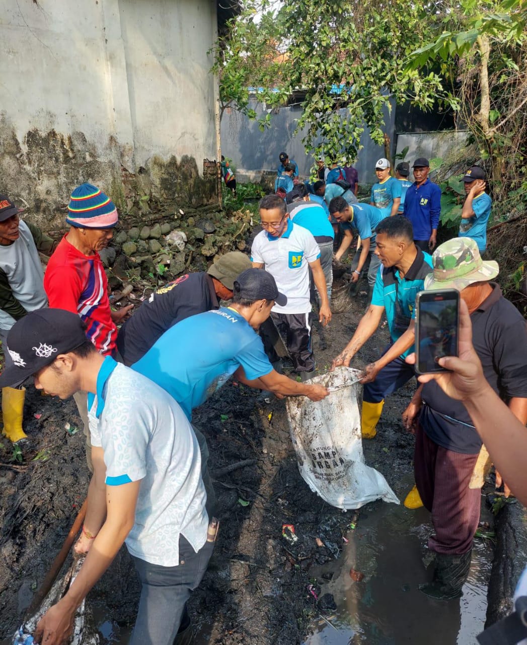 GOTONG ROYONG: Kepala Dinas PU Pengairan Guntur Priambodo bersama warga mengeruk endapan sungai dekat Pasar Rogojampi Jumat (14/6)