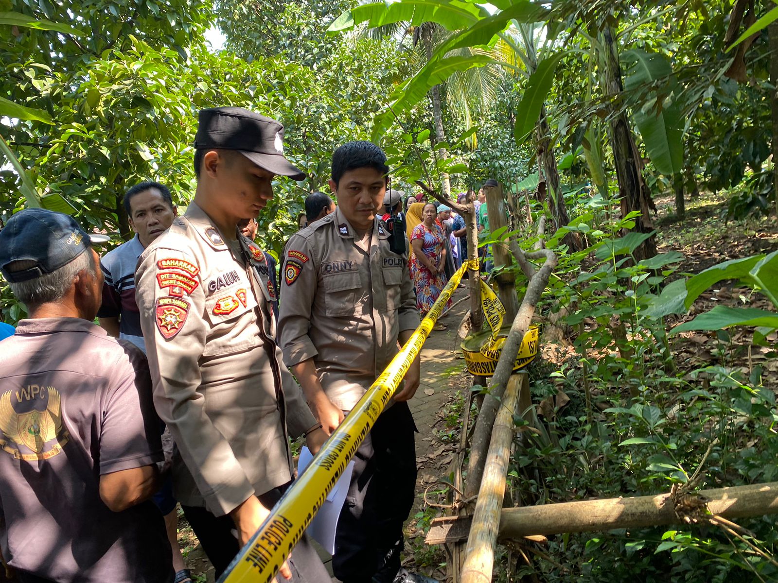 POLICE LINE: Anggota Polsek Giri memasang garis polisi di lokasi Jumali menggantung di pohon manggis Desa Jambesari, Kecamatan Giri, Sabtu (15/6).