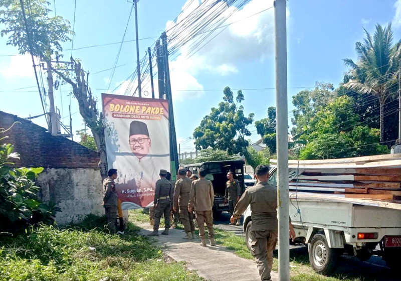 TAK BERIZIN: Anggota Satpol PP Banyuwangi nenertibkan reklame bergambar Wabup Sugirah di Jalan S Parman Banyuwangi.