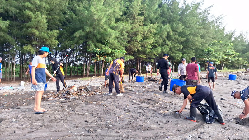 KERJA BHAKTI: Anggota Polsek Muncar bersama TNI AD, TNI AL, dan Pokdarwis gotong royong membersihkan sampah di Pantai Gumuk Kantong, Desa Sumbersewu, Kecamatan Muncar Senin &nbsp;(24/6)