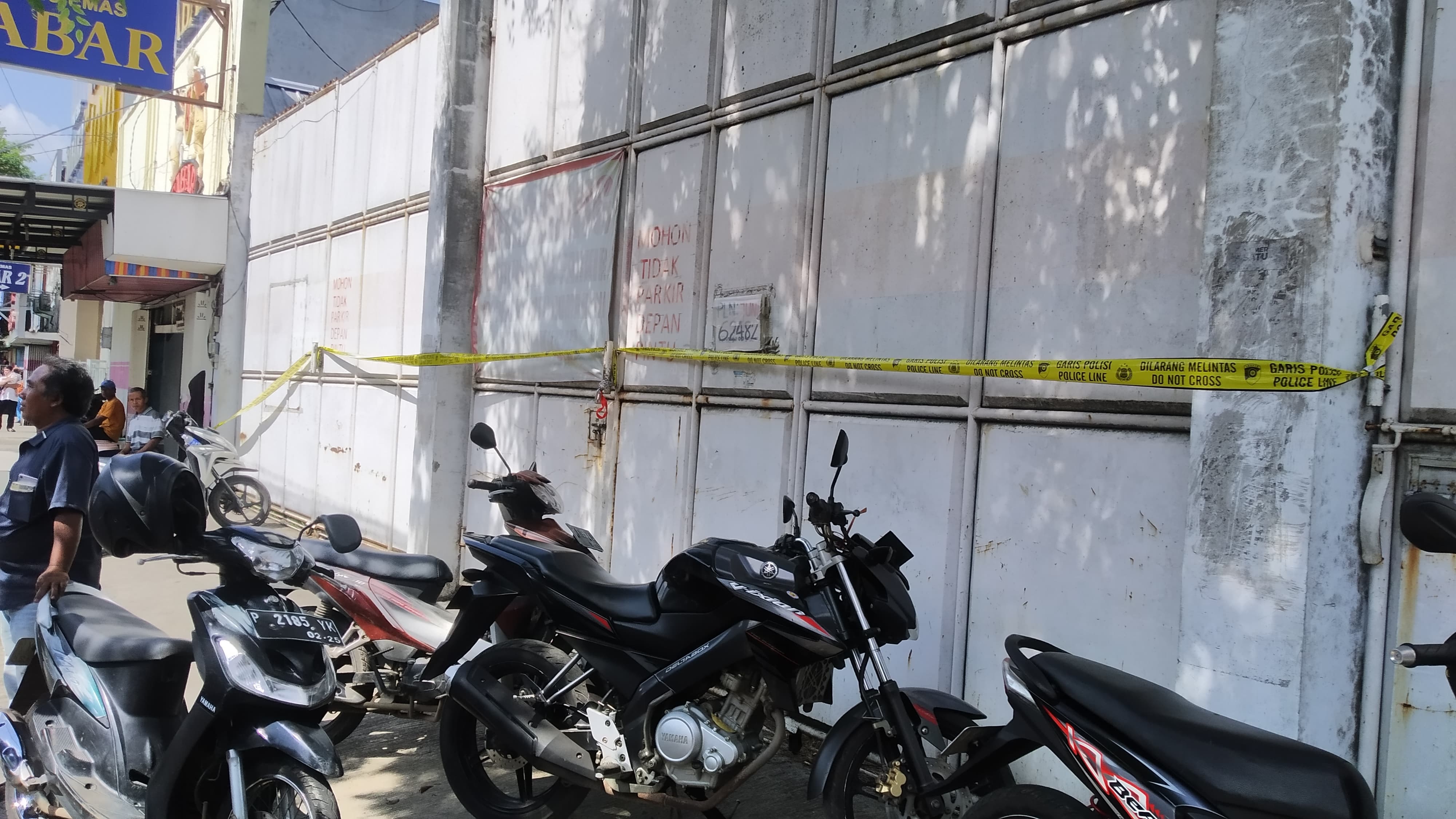 DILARANG MASUK: Pintu gerbang rumah di Jalan Gajah Mada Dusun Sawahan, Desa Genteng Kulon, Kecamatan Genteng dipasang garis polisi setelah penggerebekan pada Rabu (26/6) petang.