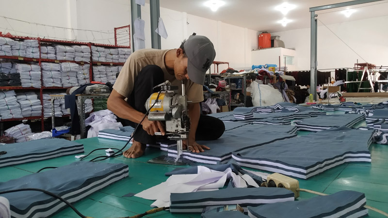SERAGAM: Salah satu pegawai sedang memotong kain untuk seragam pesanan pelanggan di industry konveksi di Dusun Cangaan, Desa Genteng Wetan, Kecamatan Genteng Selasa (9/7).