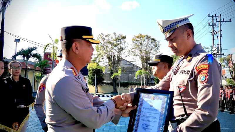 SIMBOLIS: Wakapolresta Banyuwangi AKBP Dewa Putu Eka Darmawan (kiri) menyerahkan penghargaan kepada Ipda Dwi Wijayanto di halaman Mapolresta Banyuwangi pada Selasa (16/7).