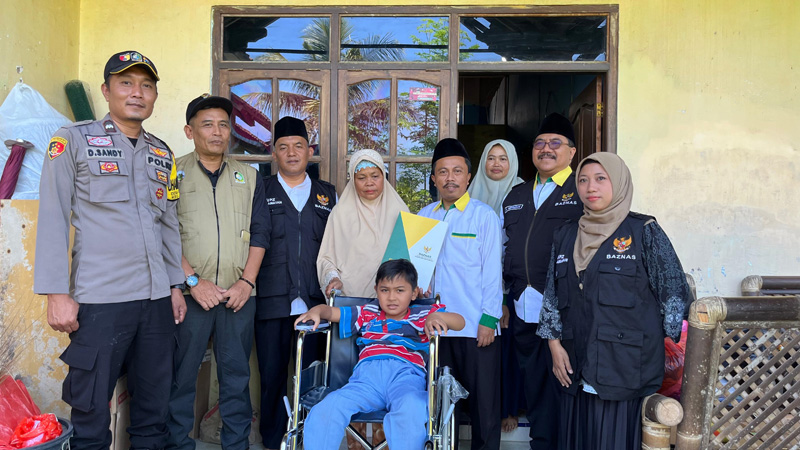 SEMOGA LEKAS SEMBUH: Ketua Baznas Banyuwangi H Lukman Hakim beserta jajaran menyerahkan bantuan kursi roda dan biaya pengobatan kepada Adi yang didampingi ibu angkatnya di Kecamatan Glenmore.