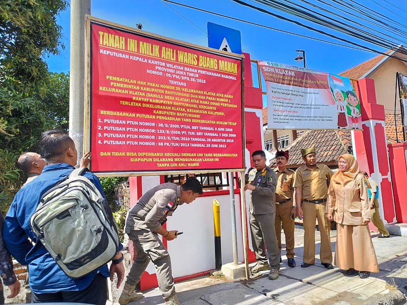 GUGATAN DITOLAK: Satpol PP disaksikan kuasa hukum pemkab Uyun Sadewa, Camat Kalipuro Astorik, dan perangkat Kelurahan Klatak menurunkan papan nama yang terpasang di depan SDN 1 Klatak Senin (29/7).
