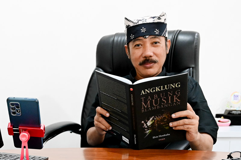 BANKIR YANG SENIMAN: Elvin Hendratha menunjukkan buku berjudul &rdquo;Angklung, Tabung Musik Blambangan&rdquo; di kantornya Jumat (9/8).