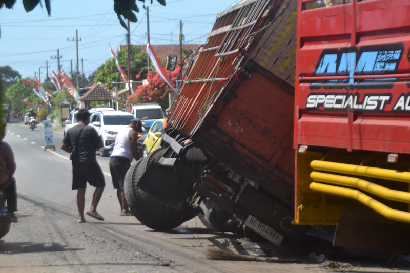 DIPERBAIKI: Roda belakang truk fuso lepas akibat patah as roda belakang hingga menyebabkan bak truk miring di jalan menikung Desa Lemahbang Kulon, Kecamatan Singojuruh Senin (12/8)