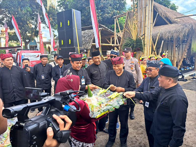 SIMBOLIS: Kepala Dispertan Banyuwangi, Arief Setyawan (tengah) menarik kupat luwar tanda memulai acara ngerujaki didampingi Kades Karangrejo, Subandriyo
