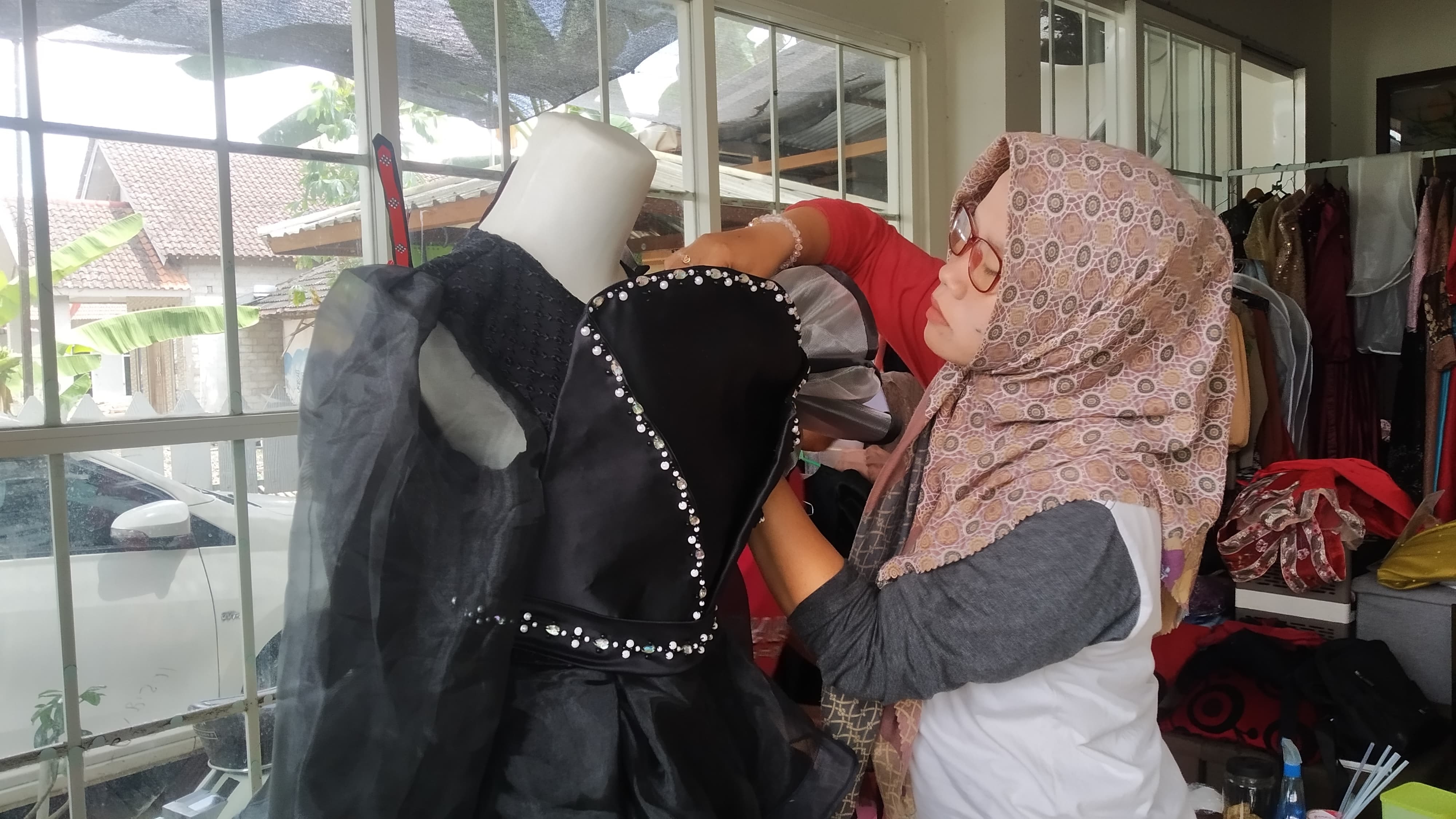LADANG CUAN: Anis Ratna Wulandari menghias kostum untuk karnaval Agustusan di Dusun Nganjukan, Desa Karangsari, Kecamatan Sempu Rabu (21/8).