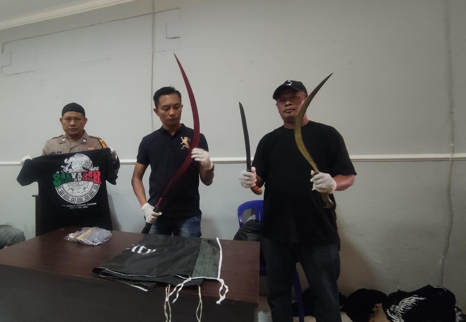 BUKTI: Kanit Reskrim Polsek Muncar Ipda Ocky Heru Prasetyo (tengah) bersama anggota menunjukkan celurit besar milik geng motor Salvador di Mapolsek Muncar Rabu (22/8)