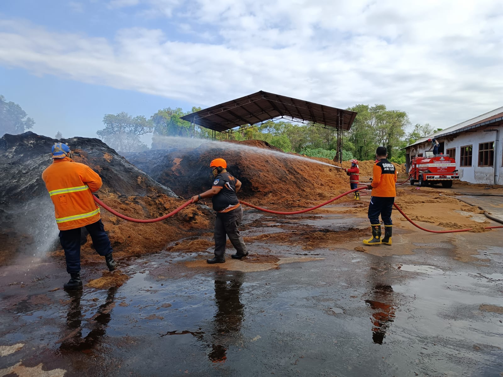 SEMPROTKAN AIR: Petugas Damkarmat memadamkan api yang membakar sekam milik PT Haka Artha Cipta Unggul di Lingkungan Sukowidi, Kelurahan Klatak, Kalipuro, Minggu (1/9).
