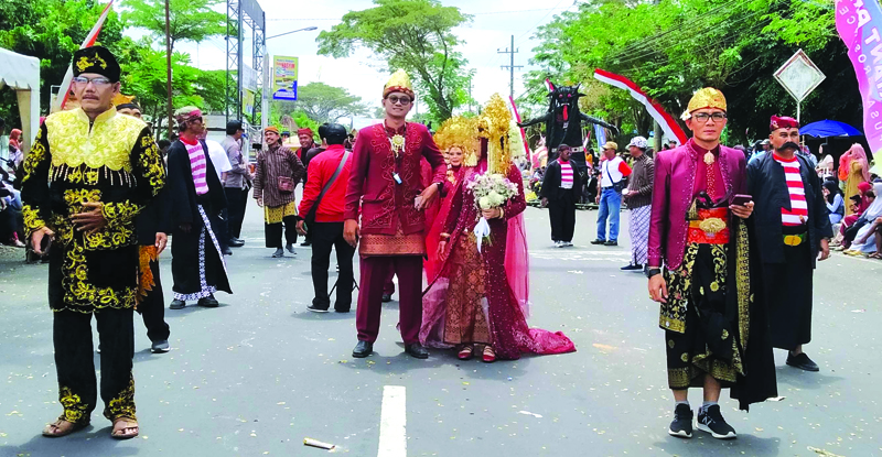 TRADISIONAL: Pj Kades Setail Mukhaerodin (kiri) dan Sekdes Muhammad Faizin mengenakan pakaian adat dalam pawai budaya di Kecamatan Genteng pada Sabtu (31/8).
