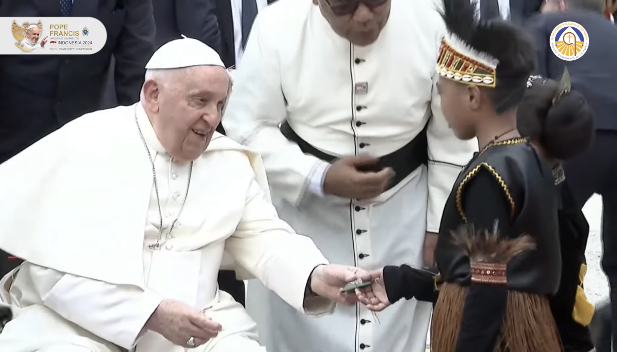 Paus Fransiskus memberikan rosario pada dua anak kecil yang memberikan bunga.
